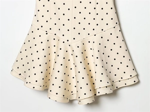 Detailed view of cream ruffled hem with classic black polka dots and flowing fabric