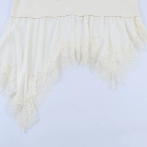 Detailed view of asymmetric hem with intricate lace trim on a cream satin top