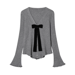 Dettaglio del cardigan in maglia grigia con fiocco di velluto e bottoni a cuore