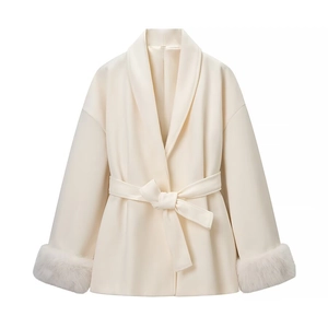Détail d'un élégant manteau croisé blanc cassé avec poignets en fourrure et ceinture nouée