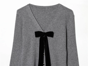Dettaglio cardigan grigio a coste con fiocco di velluto nero e bottone a cuore