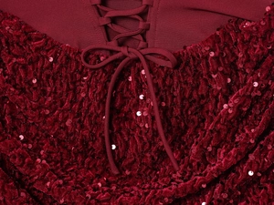 Détail du tissu en velours à paillettes rouges avec laçage et œillets métalliques