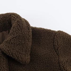 Detail of dark brown teddy fleece texture and lapel collar on long winter coat