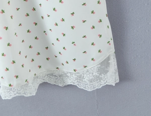 Détail de l'ourlet de robe à fleurs avec dentelle blanche et motifs floraux roses