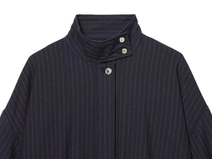 Detailed view of high stand-up collar with metal snap buttons on striped bomber jacket