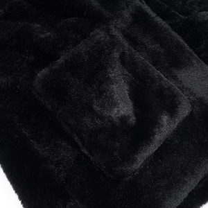 Close-up of black faux fur jacket detail featuring a soft plush texture and square pocket