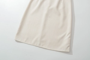 Detail view of beige lace-spliced dress hem featuring fine woven texture and neat stitching