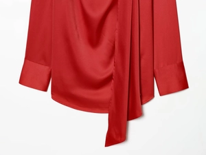 Detailed view of red satin blouse showing glossy fabric texture and flowing neck tie