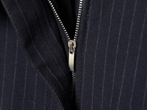 Detail of high-quality silver metal zipper on navy pinstripe bomber jacket fabric