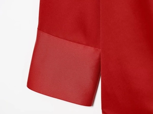 Macro shot of red satin shirt cuff featuring fine stitching and smooth fabric texture