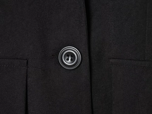 Detail of black slim-fit blazer showing fine twill texture and classic four-hole button