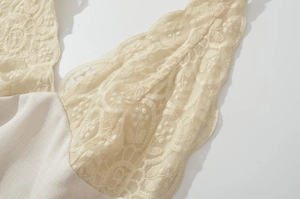 Close-up of intricate beige lace stitching and floral embroidery on a mini dress