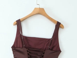 Detail of cross-back lacing on a silk-like dark brown camisole with adjustable straps