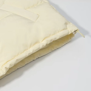 Detail of cream winter puffer jacket showing side pocket and elastic drawstring hem