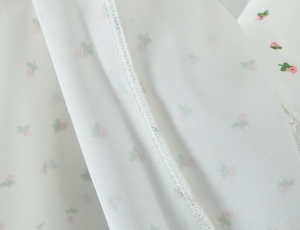 Gros plan détaillé de la couture et du motif floral rose sur tissu de robe en mousseline