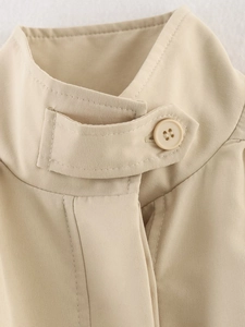 Detail of adjustable stand collar and round button on beige street style jacket