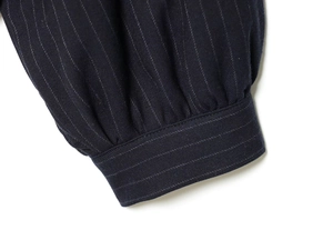 Detailed macro view of navy blue pinstripe jacket sleeve with pleated cuffs