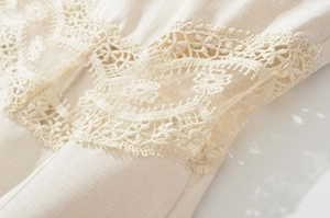 Detailed macro view of delicate lace embroidery and hollow-out floral textures on beige fabric