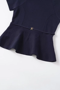 Detail of navy blue knit peplum top with fine texture and golden buckle on thin belt