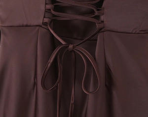 Close-up of chocolate brown satin dress back featuring lace-up design and bow detail