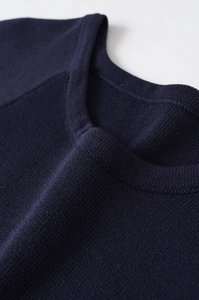 Detail of navy blue round neck and raglan sleeve stitching on fine knit sweater