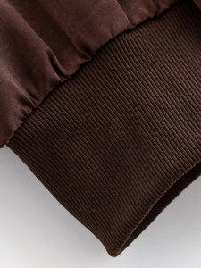 Close-up of deep brown winter jacket showing rib-knit cuff texture and thick stitching