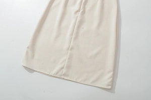 Close-up of beige linen dress hem showing natural fabric texture and neat stitching details
