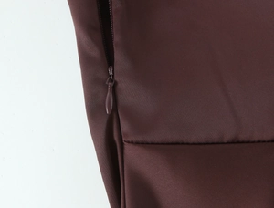 Close-up of a seamless invisible zipper detail on a dark brown woven evening dress