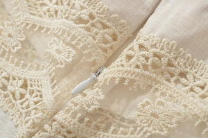 Detailed macro view of the intricate floral lace and hidden zipper on beige dress