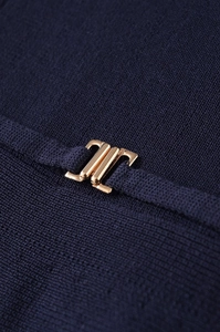 Macro detail of navy blue knit fabric with an elegant gold geometric button buckle