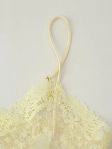 Détail de caraco en dentelle jaune pâle avec fines bretelles et bords en cils
