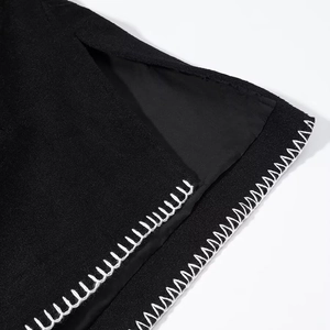 Macro detail of black wool coat with contrast white whipstitch on a side slit