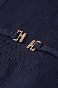 Macro detail of navy knit fabric featuring two luxury golden H-shaped metallic buckles