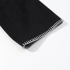 Macro shot of black garment sleeve cuff with high-contrast white stitching details