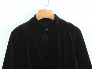 Detail of black velvet jacket with stand collar and smooth texture on a wooden hanger