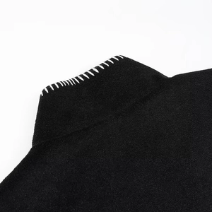 Detail of premium black wool fabric with white contrast hand-stitched embroidery on edges