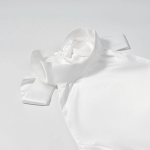 Detail of elegant white satin high-neck top featuring a large back bow and silky texture
