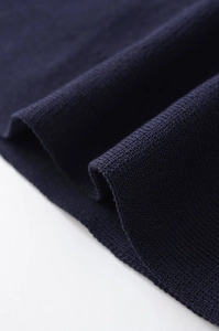 Close-up of navy blue fine knit fabric texture showing soft pleats and drape quality