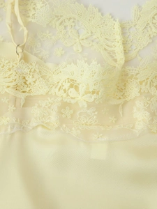 Détail d'un caraco en satin jaune clair avec dentelle florale délicate et bretelle réglable