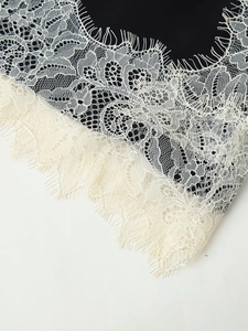 Gros plan sur tissu noir avec bordure en dentelle de cils blanche et broderie florale