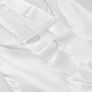 Detail of white satin dress featuring high-gloss texture and a hidden invisible zipper