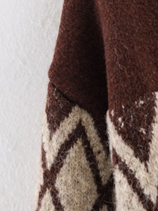 Macro shot of V-neck knit cardigan showing geometric diamond patterns and fuzzy texture