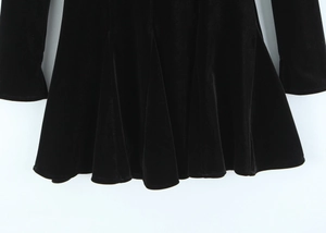 Detail of elegant black velvet dress hem with soft pleats and glossy fabric texture
