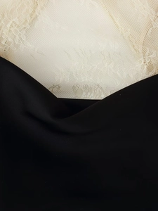 Détail du contraste entre le satin noir lisse et la dentelle blanc cassé délicate