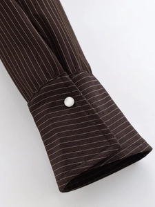 Close-up of a striped cuff with a pearl button on a casual dark coffee shirt