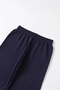 Detail of dark blue knitted trousers featuring high elastic waistband and premium texture
