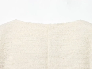Macro shot of off-white tweed jacket with textured grain fabric and straight neckline detail