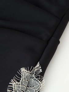 Détail de la bordure en dentelle blanche cousue sur un tissu noir de qualité
