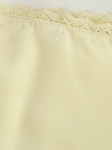 Gros plan sur tissu satiné beige avec bordure en dentelle crochetée et coutures soignées