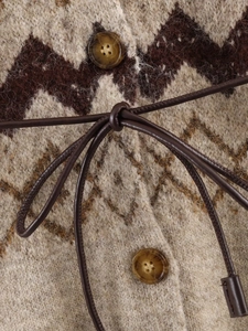 Close-up of knit cardigan with marble buttons and dark brown leather waist tie detail